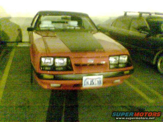 Red Ford Mustang with black hood stripe parked in a lot