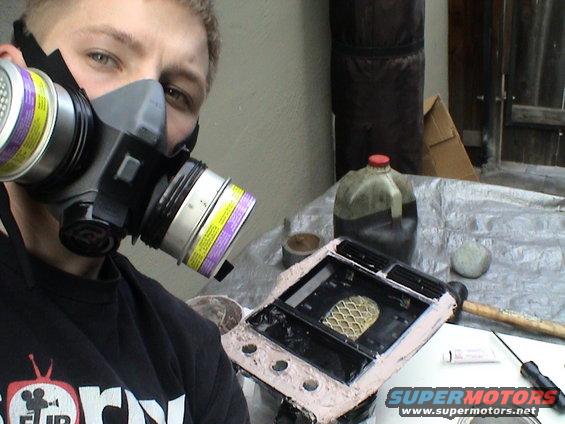 Person in respirator works on black car center console with tan putty and mesh insert