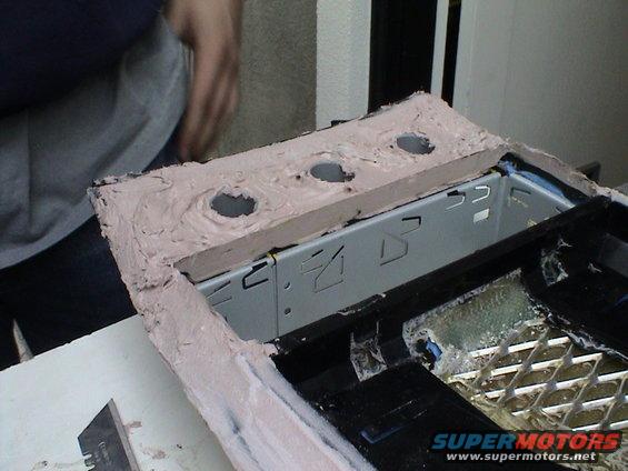 Custom center console modification with three circular cutouts and a metal bracket