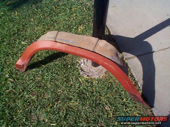Red fender trim piece resting on grass next to a concrete path
