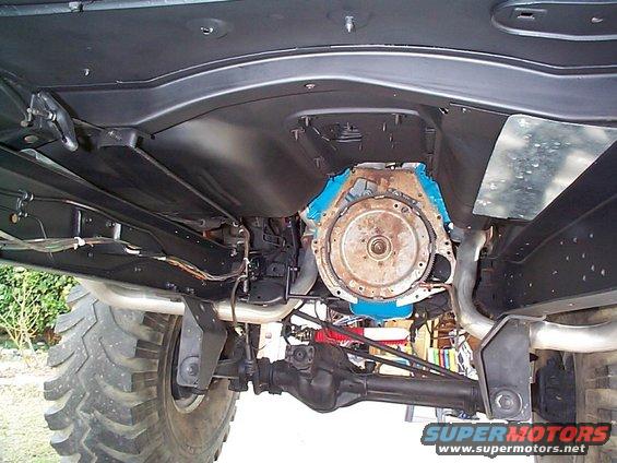 Underside view of vehicle engine and drivetrain, with large tires