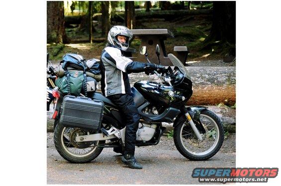 Side view of a black motorcycle with luggage and a rider wearing a helmet