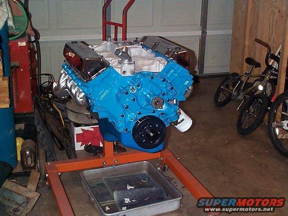 Blue V8 engine on an orange engine stand with chrome valve covers