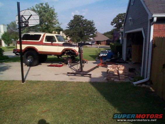 1978 Ford Bronco lifted with engine out, parked in driveway next to garage