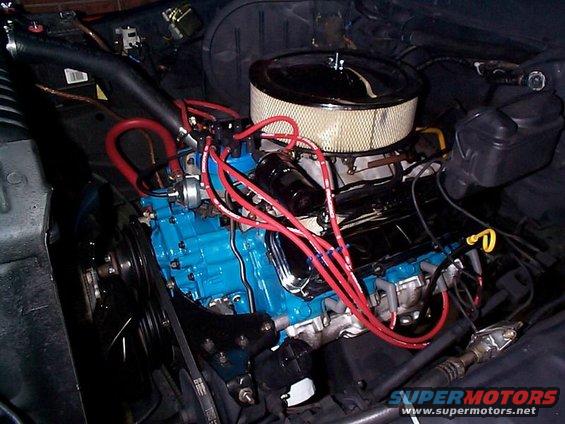 Engine bay showing a blue engine block, air filter, and red spark plug wires
