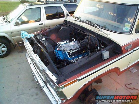 1979 Ford Bronco with hood open, showing a blue engine and missing front wheel