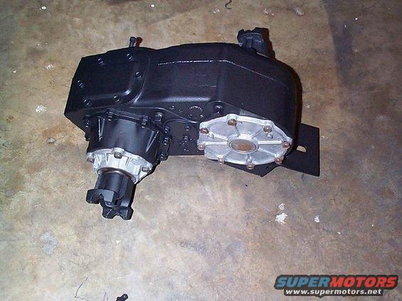 Black transfer case with silver output flanges on a concrete floor