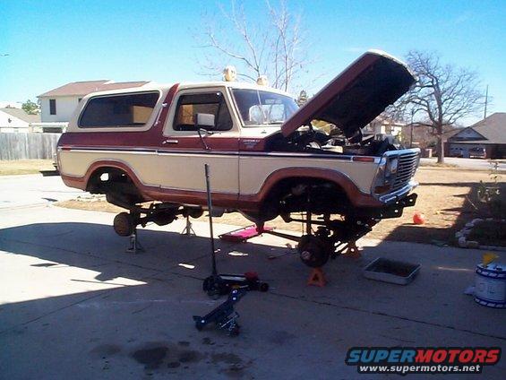 1979 Ford Bronco on jack stands with hood open, undergoing repairs in a driveway