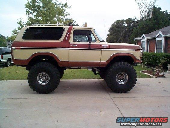 Lifted two-tone red and tan Ford Bronco with large tires parked in a driveway