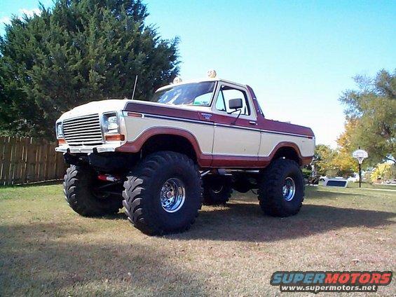 Lifted 1978 Ford Bronco with two-tone paint and large off-road tires parked on grass