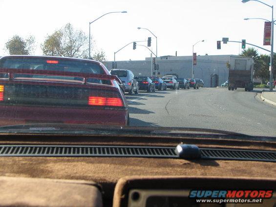 Red sports car with a spoiler and distinctive taillights in traffic
