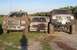 2000 Ford Excursion - Three muddy trucks are parked side-by-side on a grassy area under a clear sky.