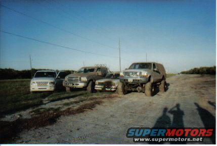Silver 2000 Ford Excursion with lifted suspension, parked on a dirt road