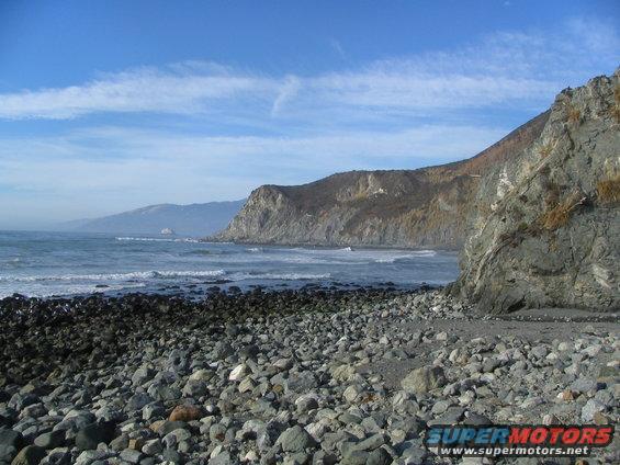 Rocky beach with ocean waves and cliffs under a blue sky