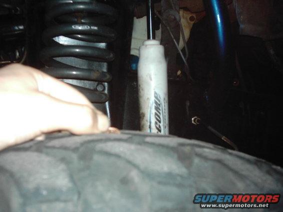 Close-up of a tire, coil spring, and shock absorber with 'COMP' written on it