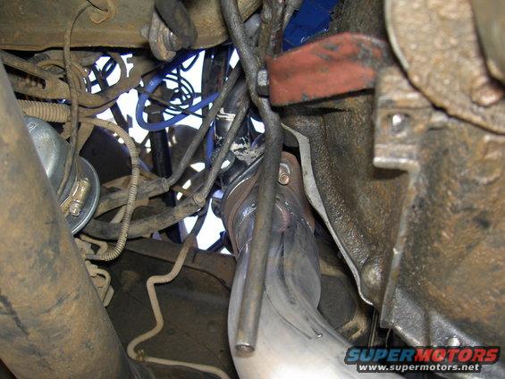 Vehicle engine components, including exhaust pipe and wiring, with Supermotors.net watermark