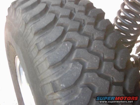 Close-up of a knobby off-road tire and a black coil spring