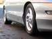 1994 Ford Probe - The side profile of a silver 1994 Ford Probe is visible, with a focus on the front wheel and lower body trim.