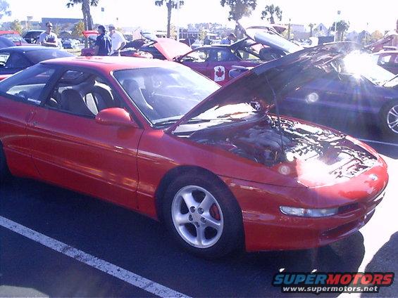 Red 1995 Ford Probe with hood open, parked next to other cars