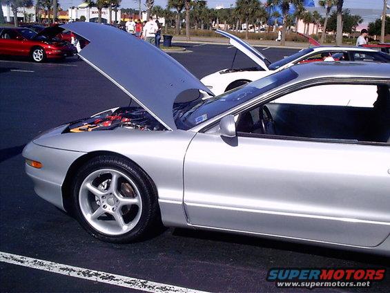 Silver 1995 Ford Probe with hood open, parked next to a white car with hood open. Another red car is visible in the background