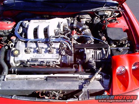 Red 1995 Ford Probe engine bay with V6 engine, Ford branding, and fuse box