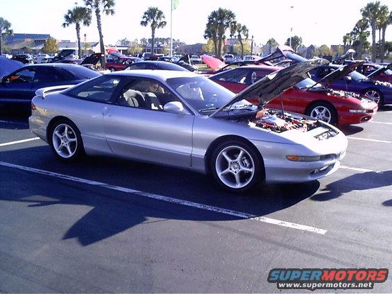 Silver 1995 Ford Probe with hood open, parked at a car show