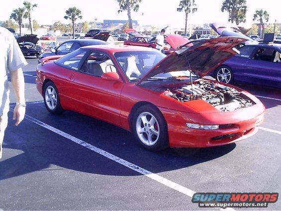Red 1995 Ford Probe with hood open, parked in a lot with other cars