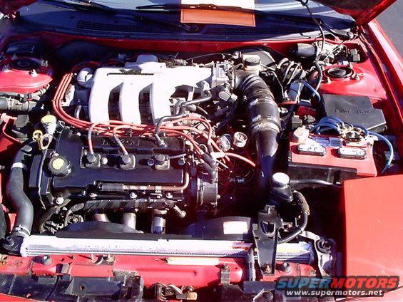 Red engine bay with black engine block, white intake manifold, and red spark plug wires