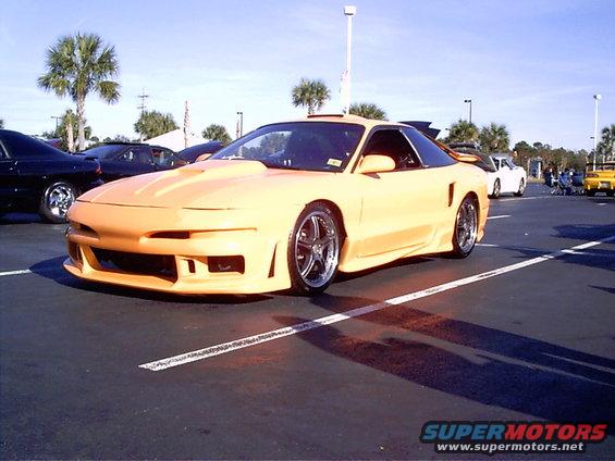 Yellow 1995 Ford Probe with aftermarket body kit and hood scoop, parked in a lot