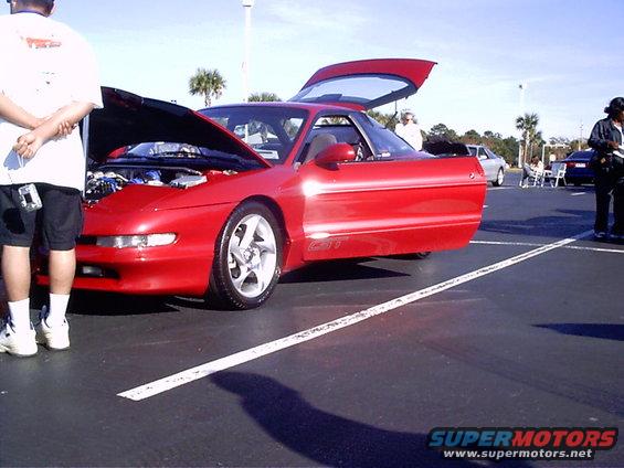 Red 1995 Ford Probe GT with hood and driver door open. Person standing to the left