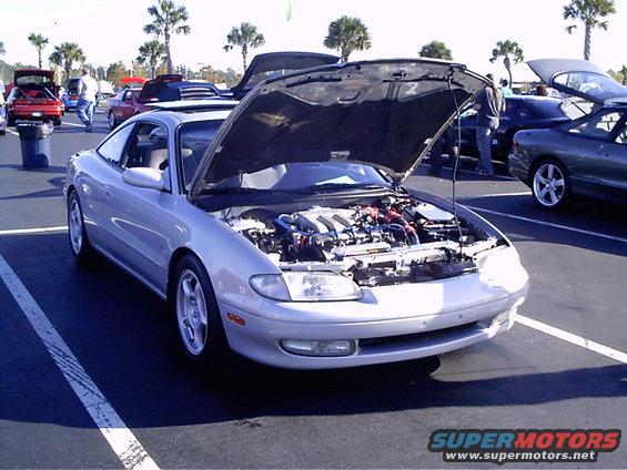 Silver Mazda MX-6 with hood open showing engine bay. Other cars parked nearby
