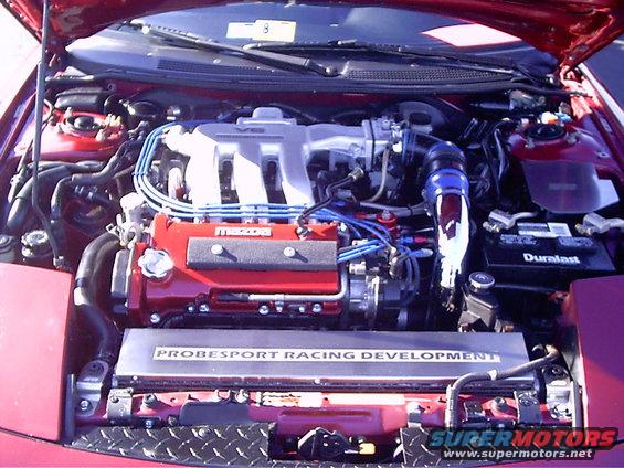Red engine bay with V6 intake manifold, red valve covers, and "PROBESPORT RACING DEVELOPMENT" plate