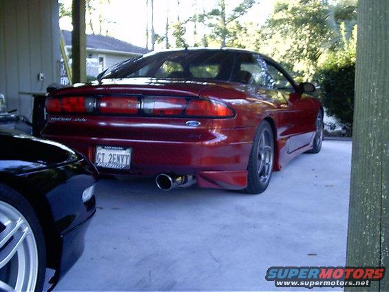Red Ford Probe parked next to a black car. Rear view shows taillights, spoiler, and license plate
