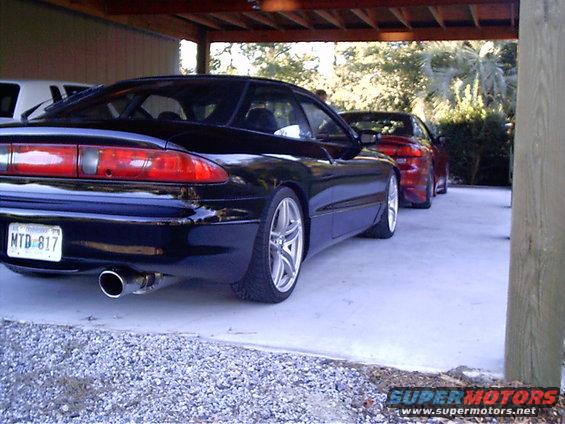 Black 1995 Ford Probe rear quarter view with a red car behind it