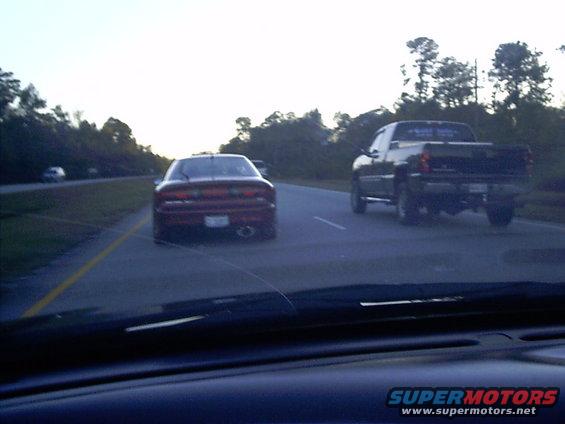 Red sports car and black pickup truck driving on a highway