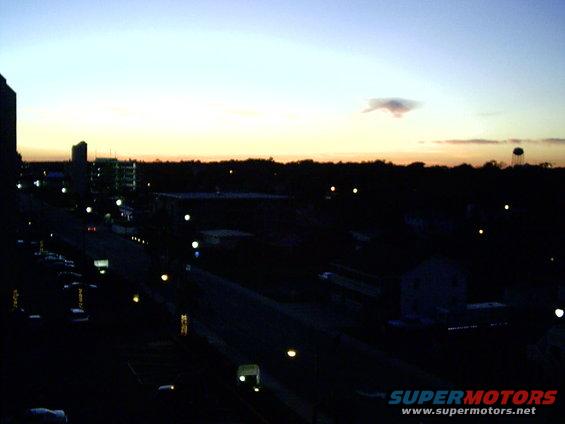 city street and buildings at dusk with a water tower in the distance