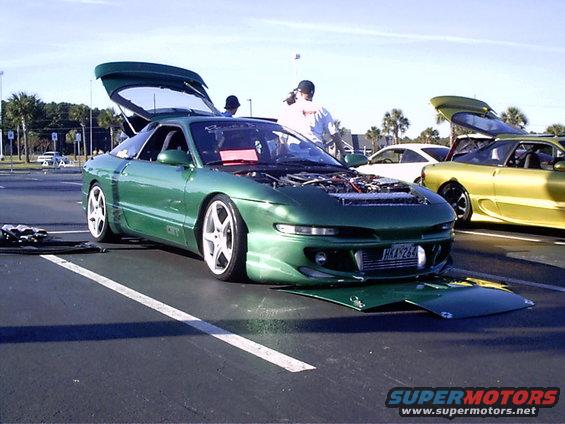Green 1995 Ford Probe with hood and trunk open, front bumper detached, parked on asphalt