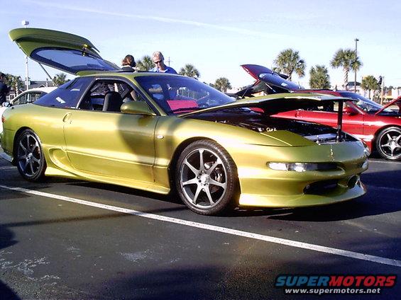 Lime green 1995 Ford Probe with hood and trunk open, parked next to a red car