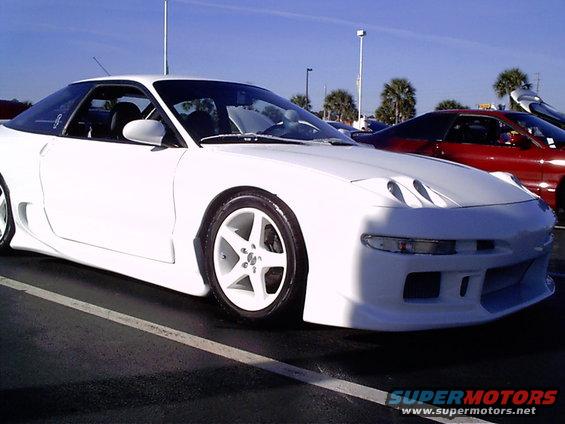 White 1995 Ford Probe with body kit parked in a lot, red car behind it