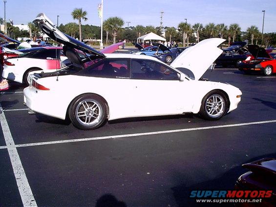 1995 Ford Probe coupe, white, hood and trunk open, parked at car show. Other cars visible