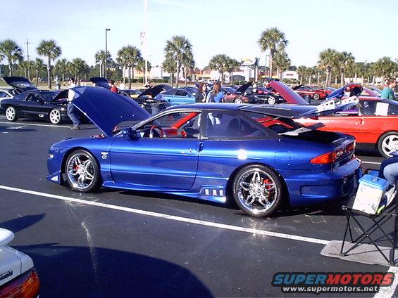 Blue 1995 Ford Probe with hood up, parked at car show with other cars