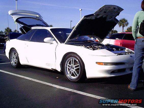 White 1995 Ford Probe with hood and trunk open, parked on asphalt. Aftermarket wheels are visible