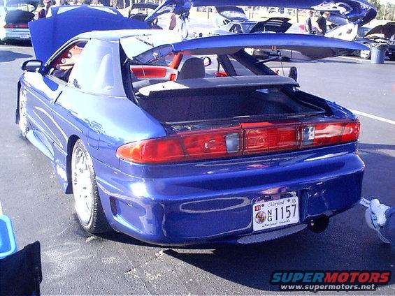 Blue sports car with a large rear spoiler and custom body kit, viewed from the rear