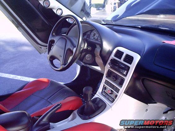 Car interior shows red and black seats, aftermarket stereo, and gauges on the door panel