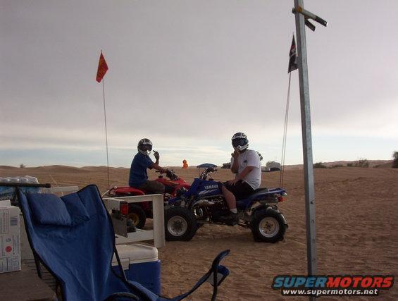 Blue Yamaha ATV with rider, red ATV with rider, desert dunes, cloudy sky