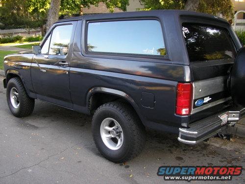 Dark blue Ford Bronco parked on street, rear quarter view. Visible Ford badge on tailgate