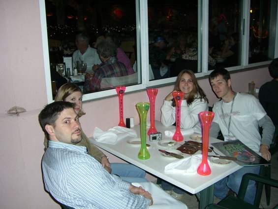 Four people sit at a table with tall novelty cups. Two men and two women are visible