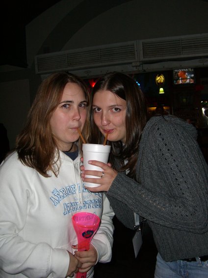Two women share a large drink with straws