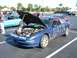 1996 Ford Probe - A blue 1996 Ford Probe is parked with its hood and trunk open, displaying a guitar in the engine bay.