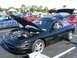 1996 Ford Probe - A black 1996 Ford Probe GT is displayed with its hood and trunk open at a car show, with other vehicles in the background.